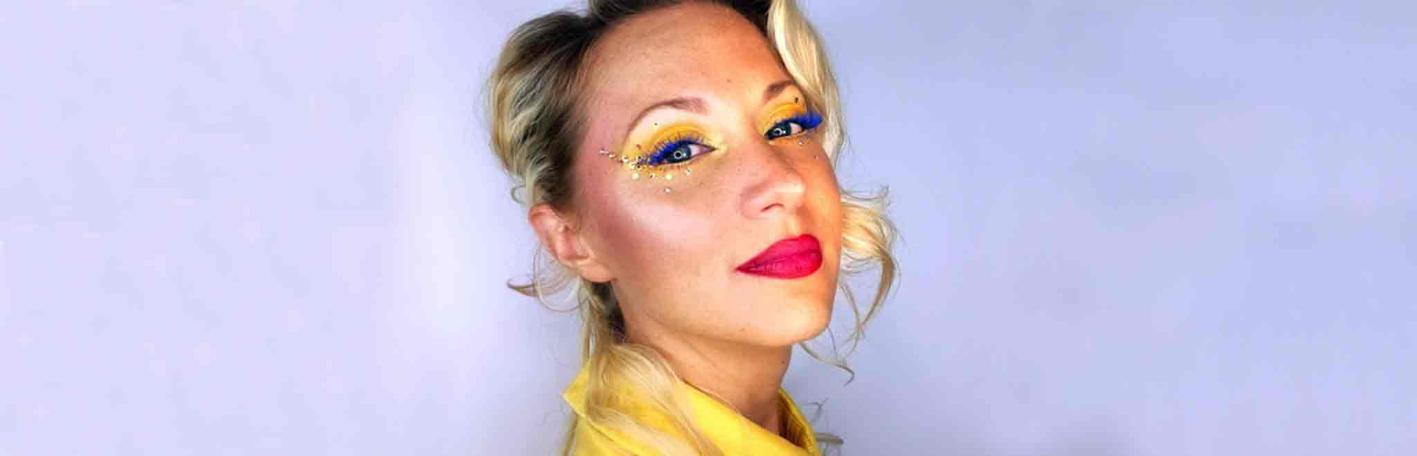 Femme blonde avec maquillage jaune mascara bleu et bouche ombrée rose et rouge